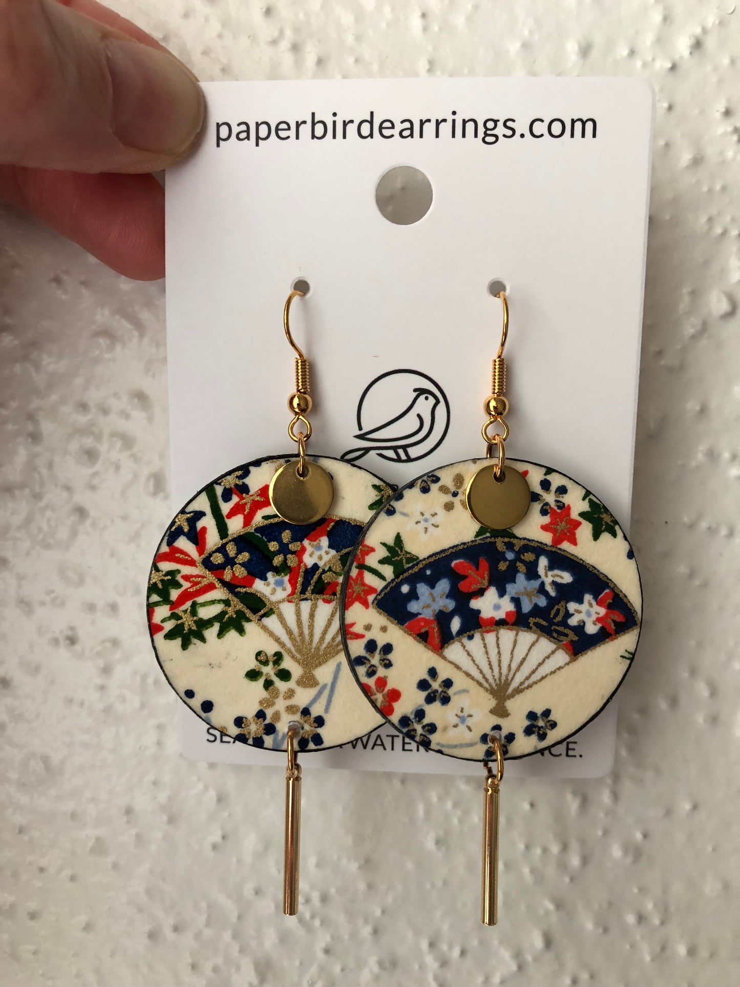 paper earrings on beige background with a blue bamboo fan design