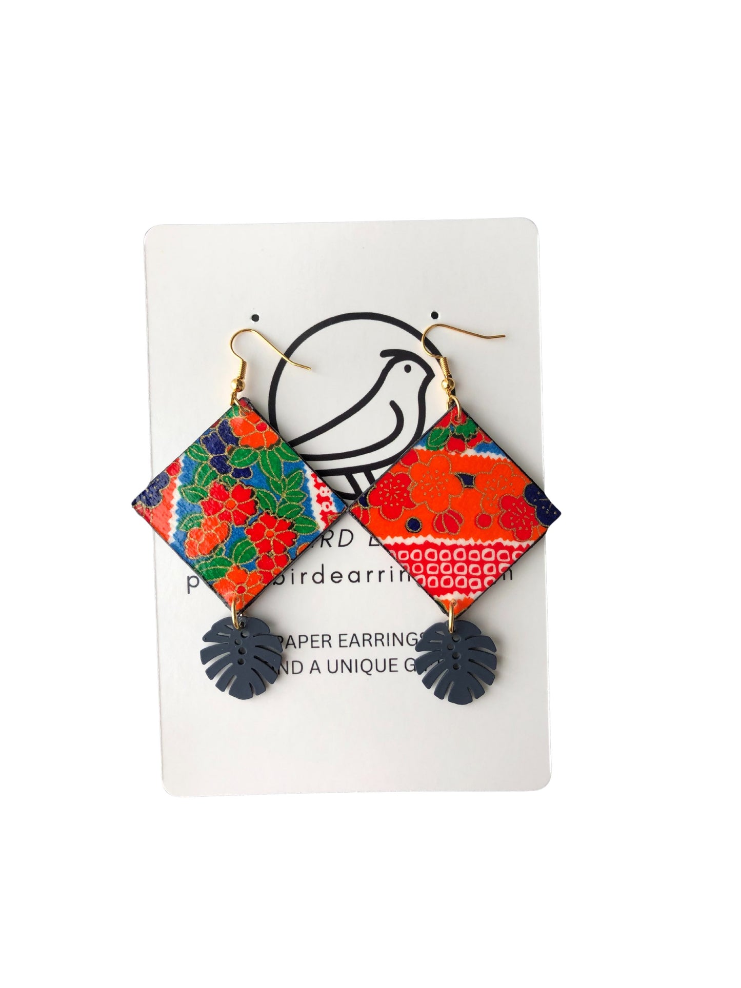 Colorful geometric paper earrings on a white card with a bird design.
