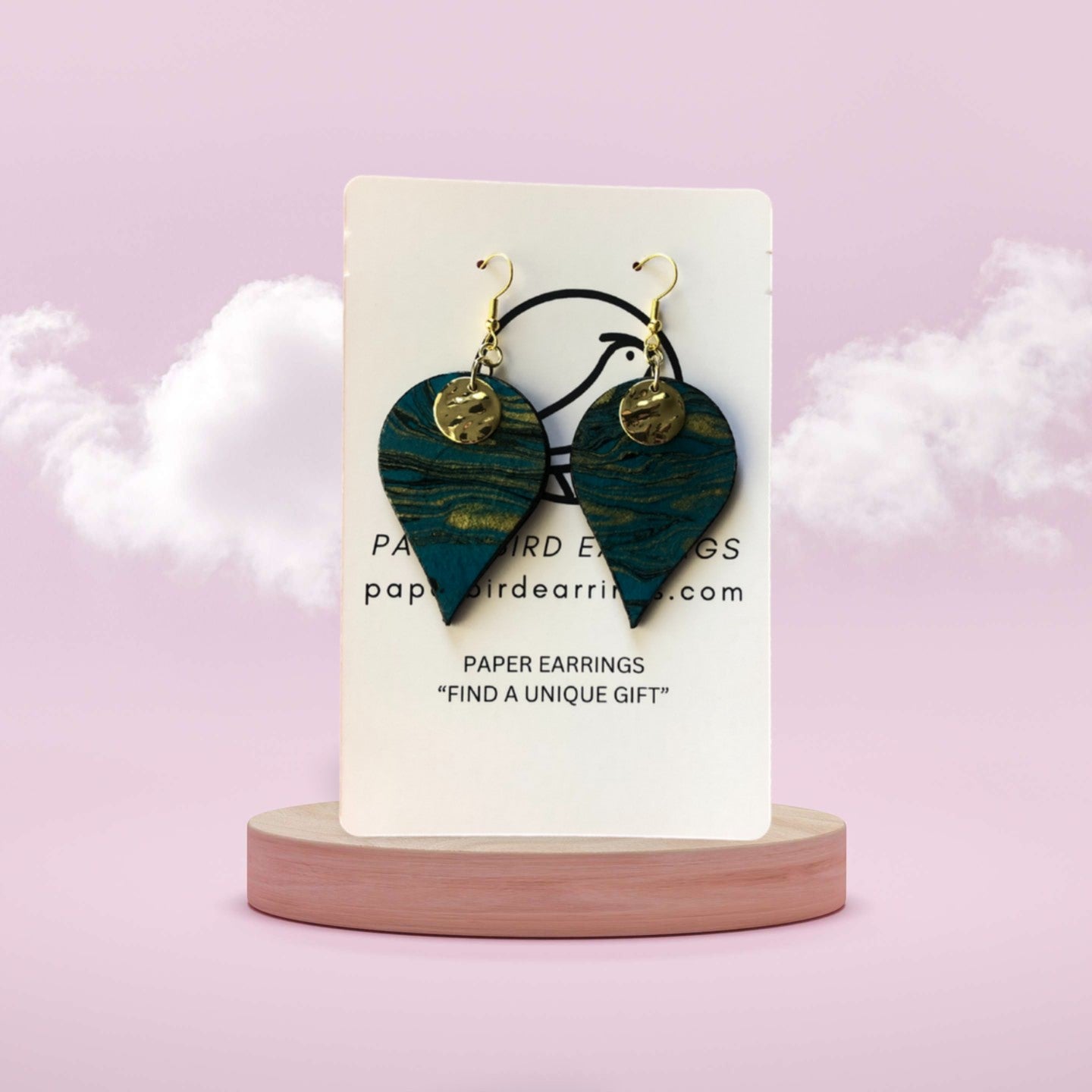 Heart-shaped paper earrings on a display card with a pink background