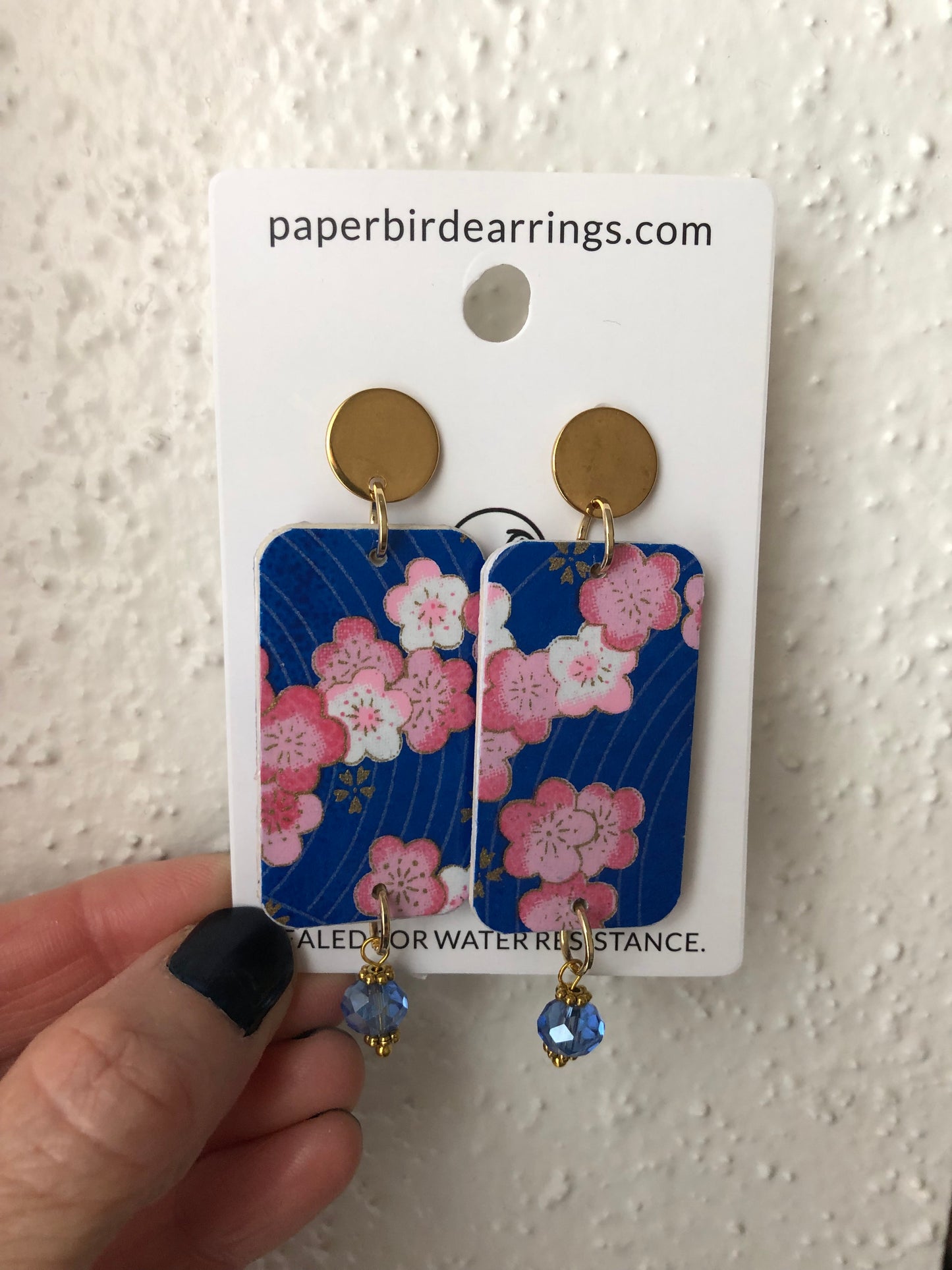 handmade paper earrings with cherry blossoms design on blue paper