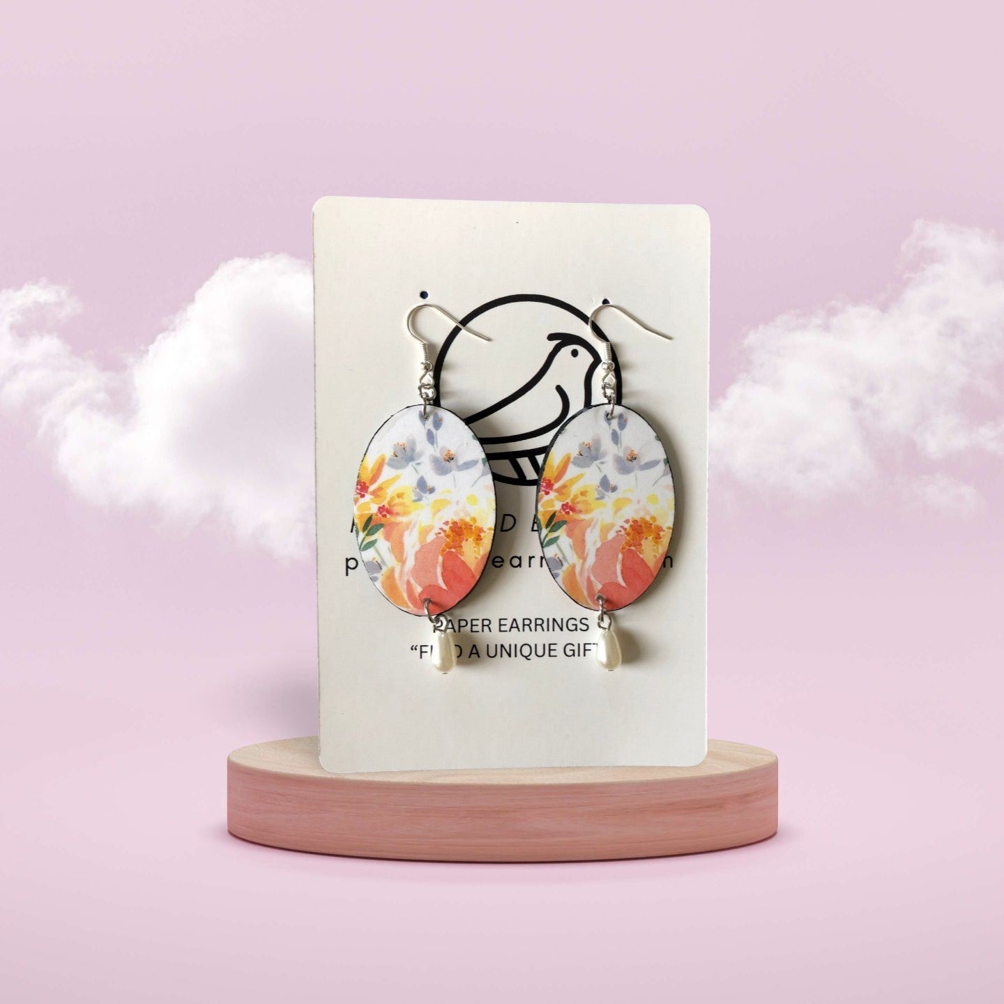 Floral earrings on a display card with a pink background