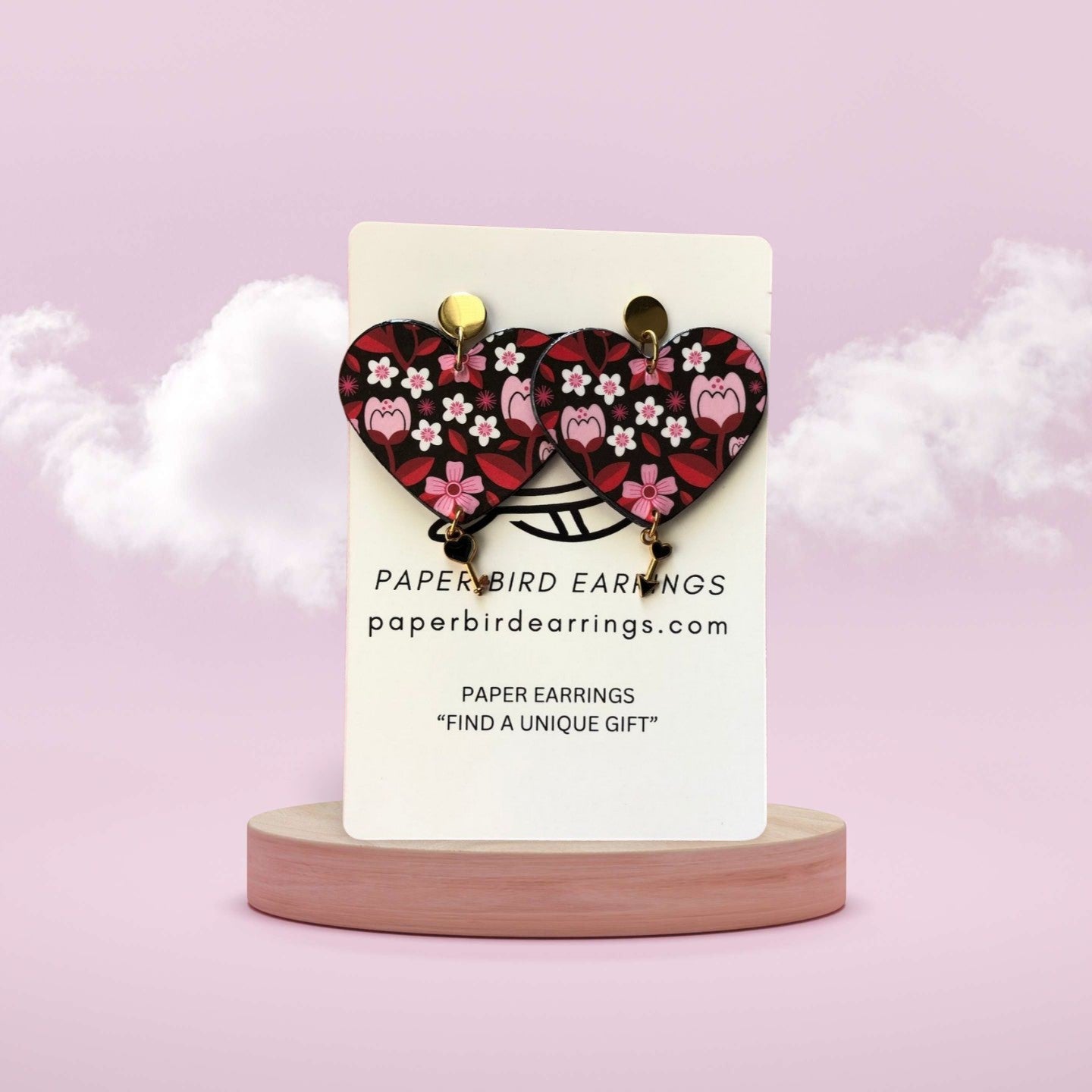 Heart-shaped earrings on a stand with a pink background