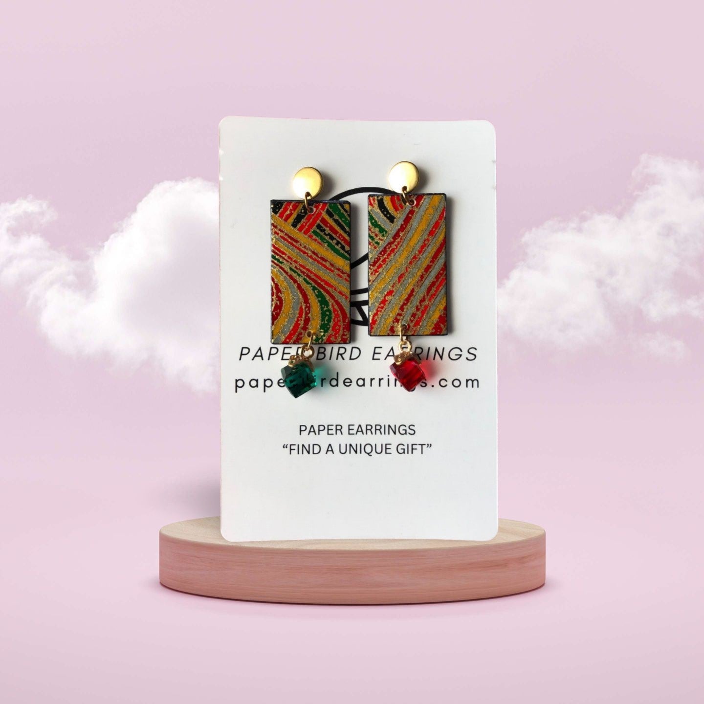 Colorful paper earrings on a white card with 'Papertbird Earrings' branding against a pink background.