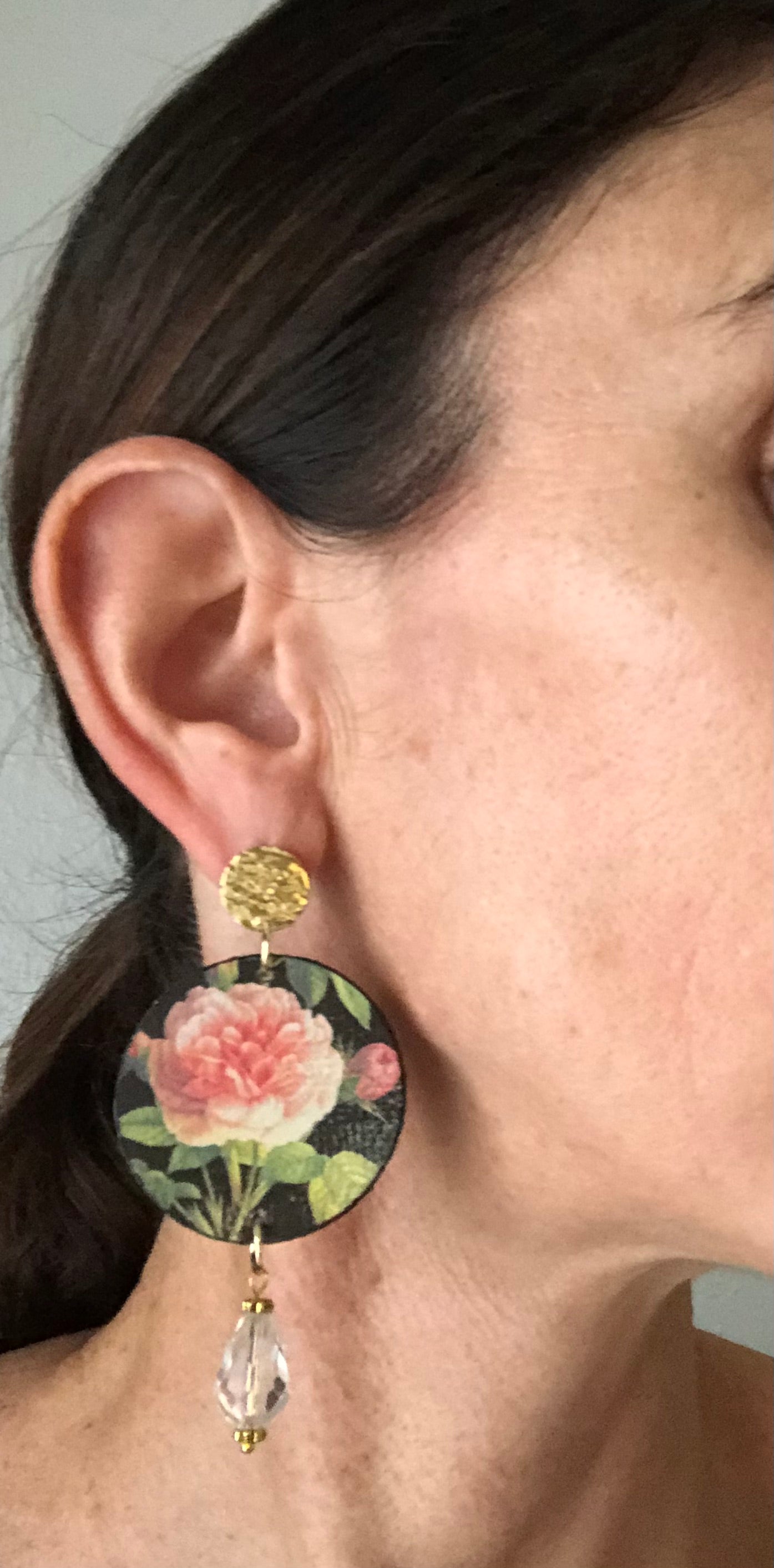 Close-up of ear wearing floral earring with crystal drop.