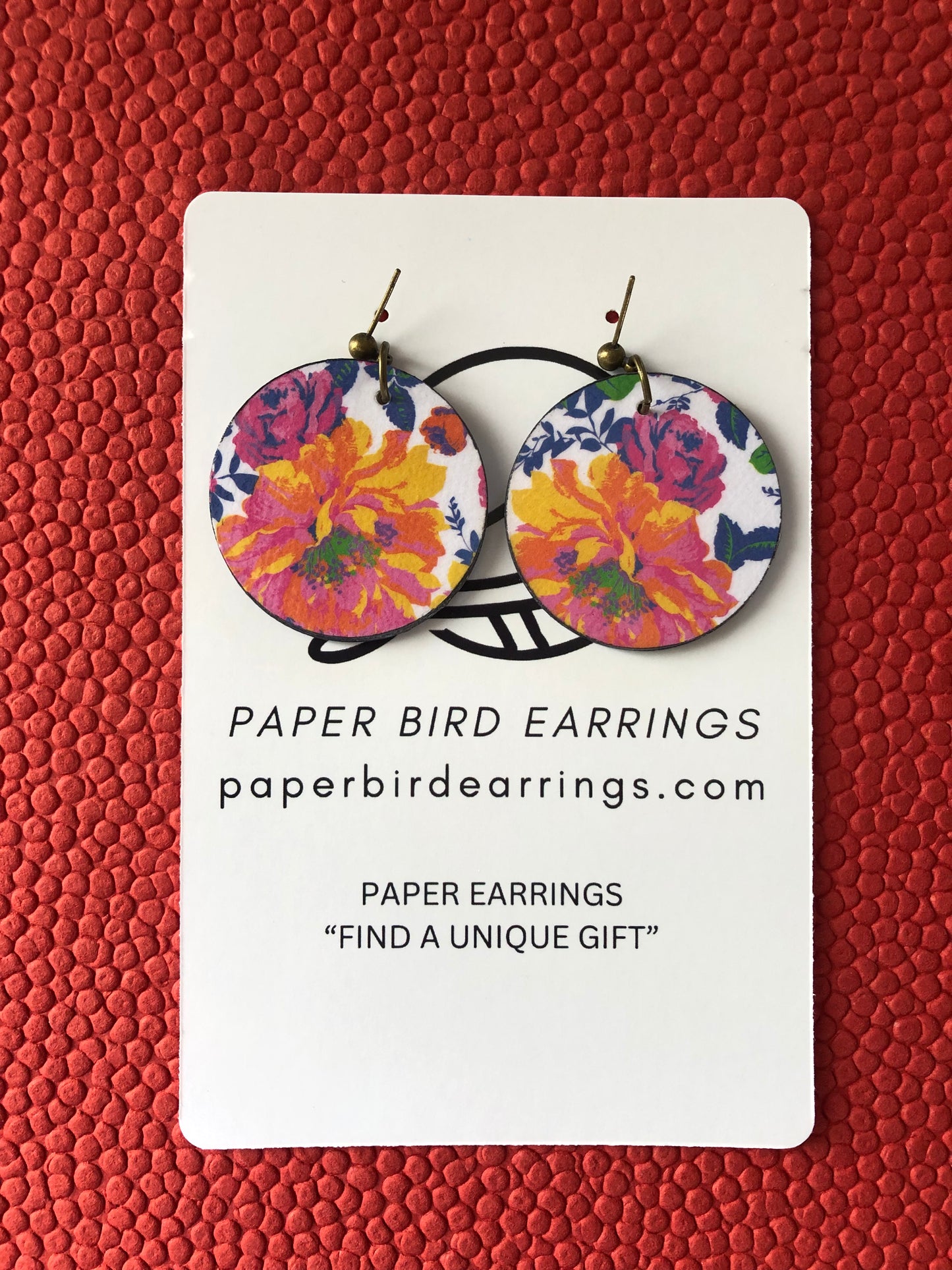 Floral paper bird earrings on a red textured background
