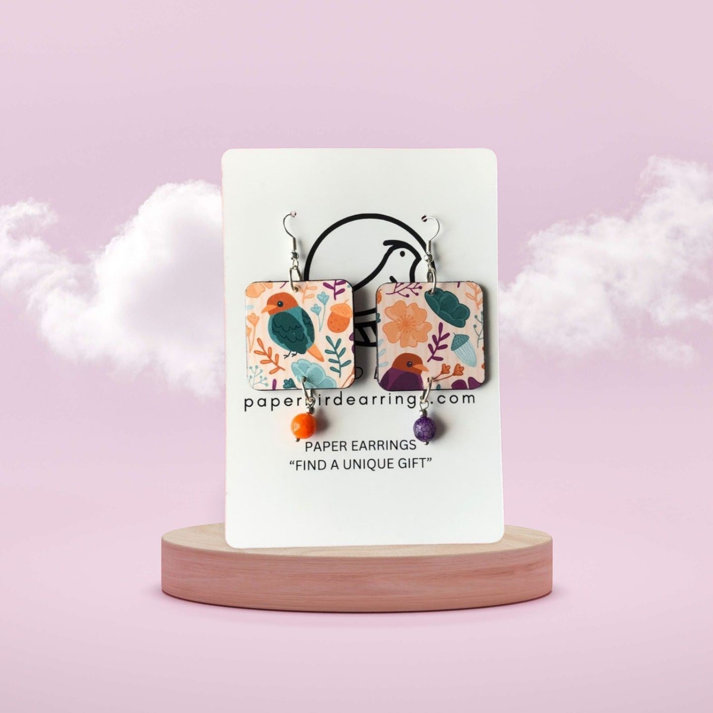 Pair of floral paper earrings on a display card with a pink background