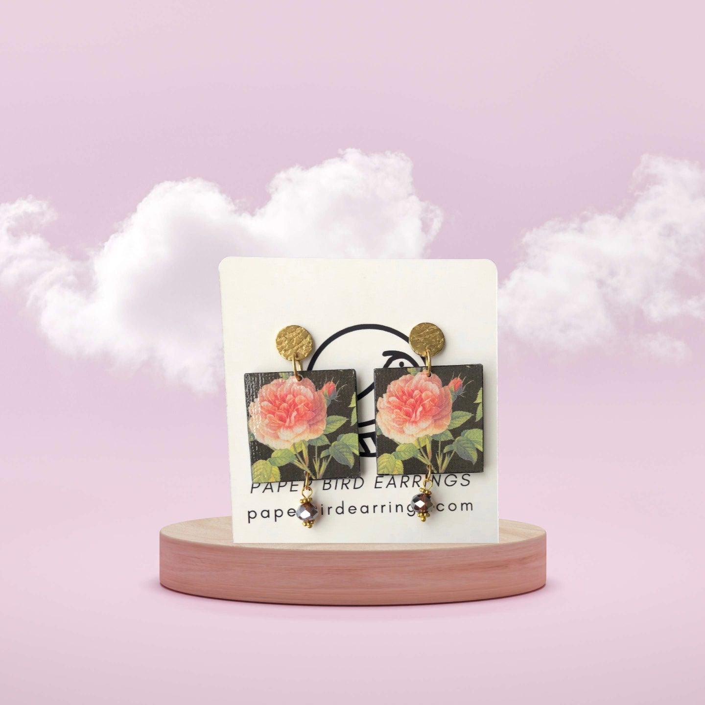 Floral earrings on a card with a pink background
