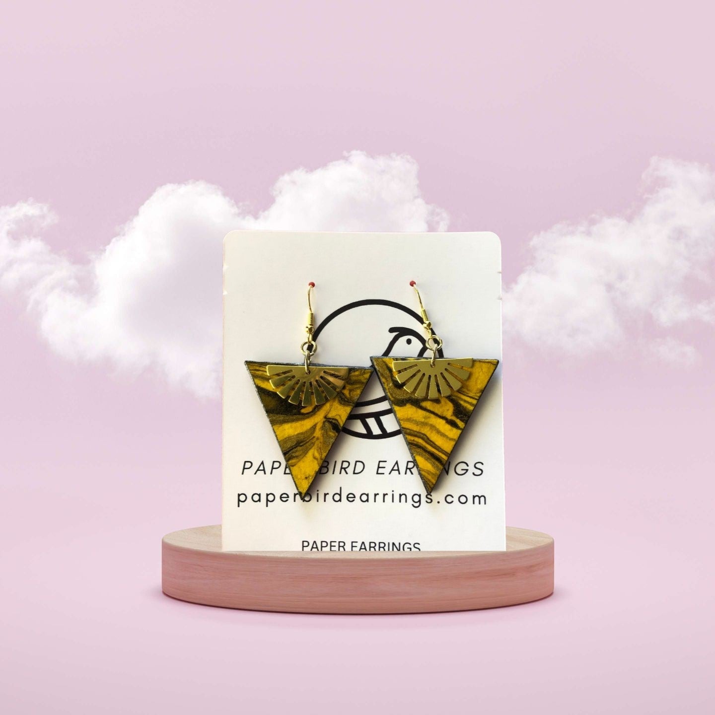 Triangle-shaped earrings on a card with 'Paper Bird Earrings' branding against a pink background