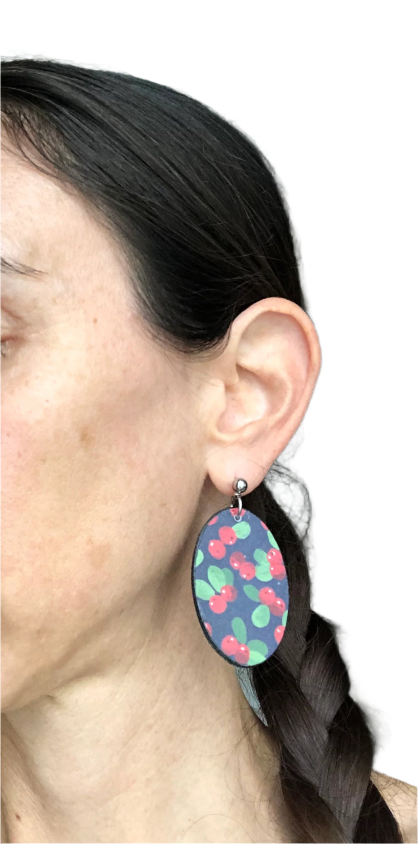 Close-up of a person wearing colorful earrings with a neutral background