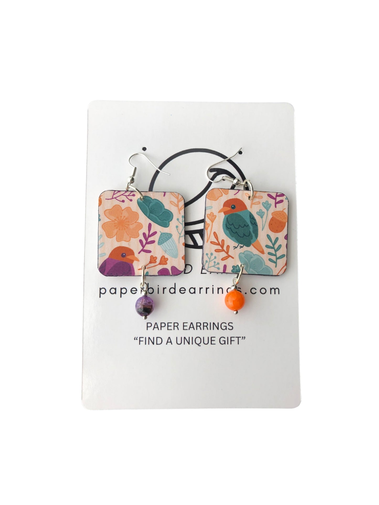 Pair of colorful paper earrings on a white card with branding text.