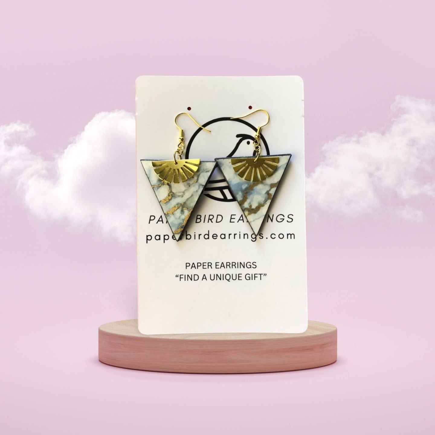 Triangular earrings on a display card with a pink background