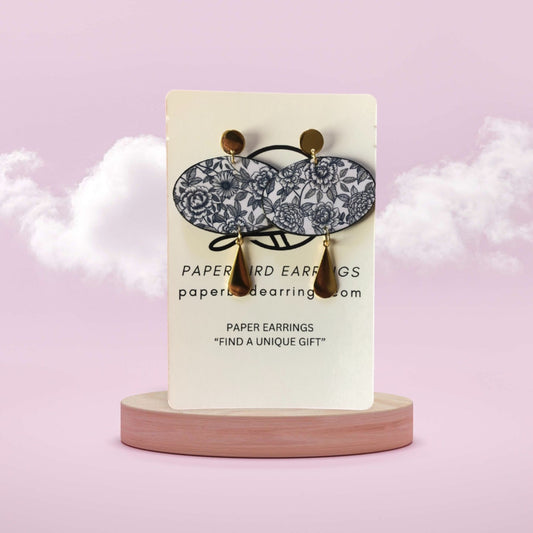 Pair of paper earrings on a display card with a pink background