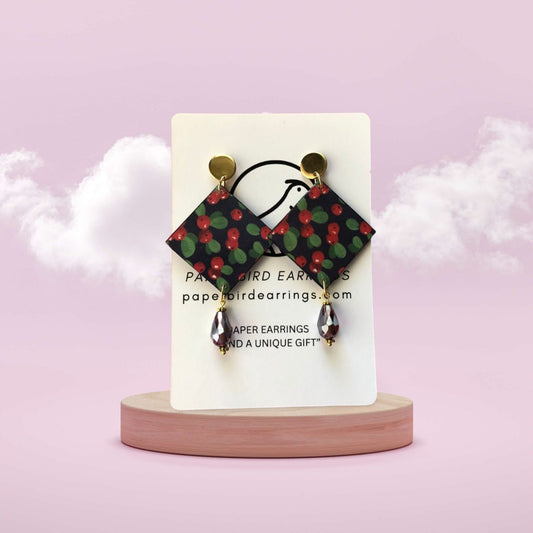 Earrings on a display card with a pink background
