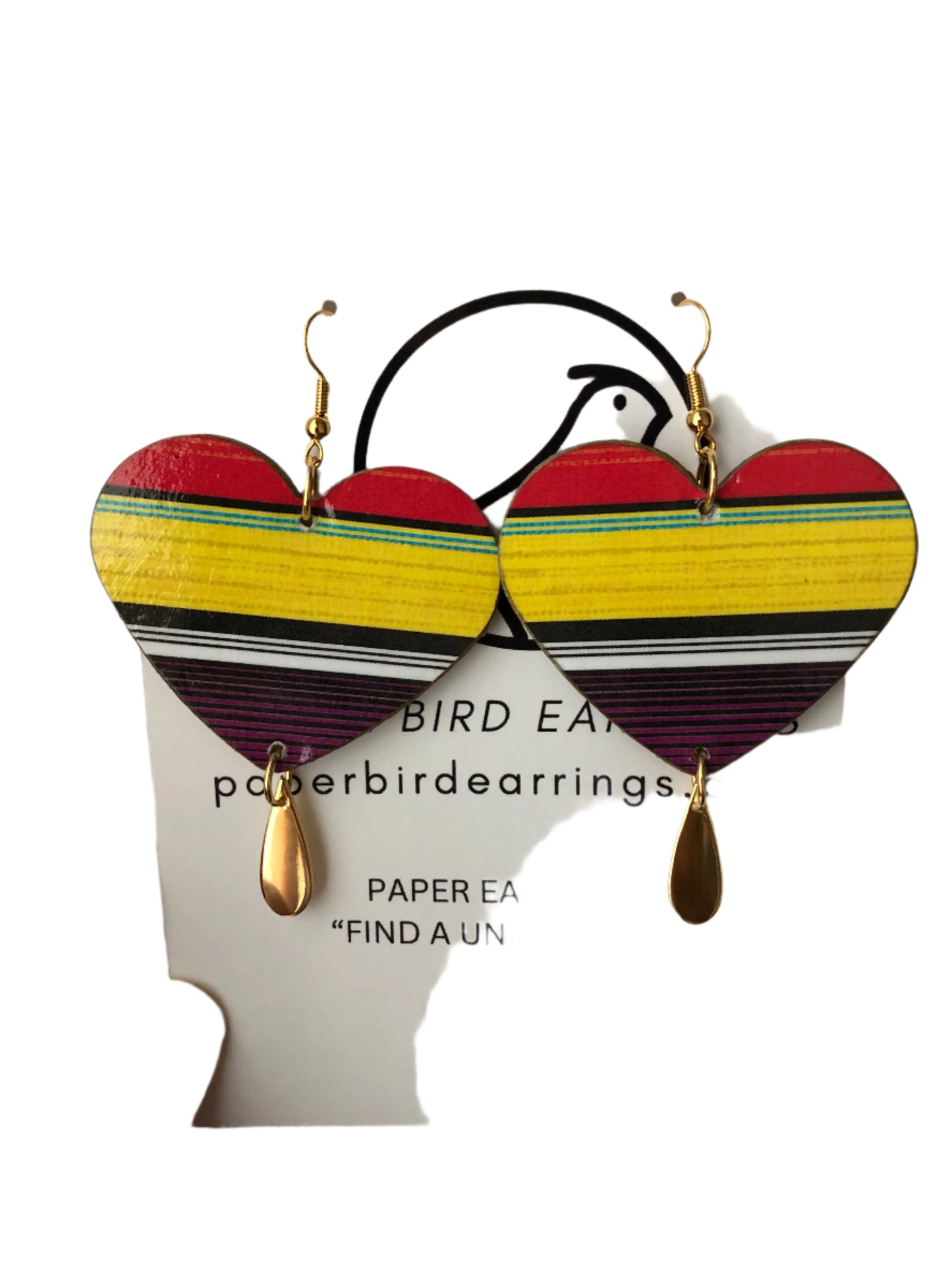 Colorful paper earrings on a card held by a hand against a textured white background