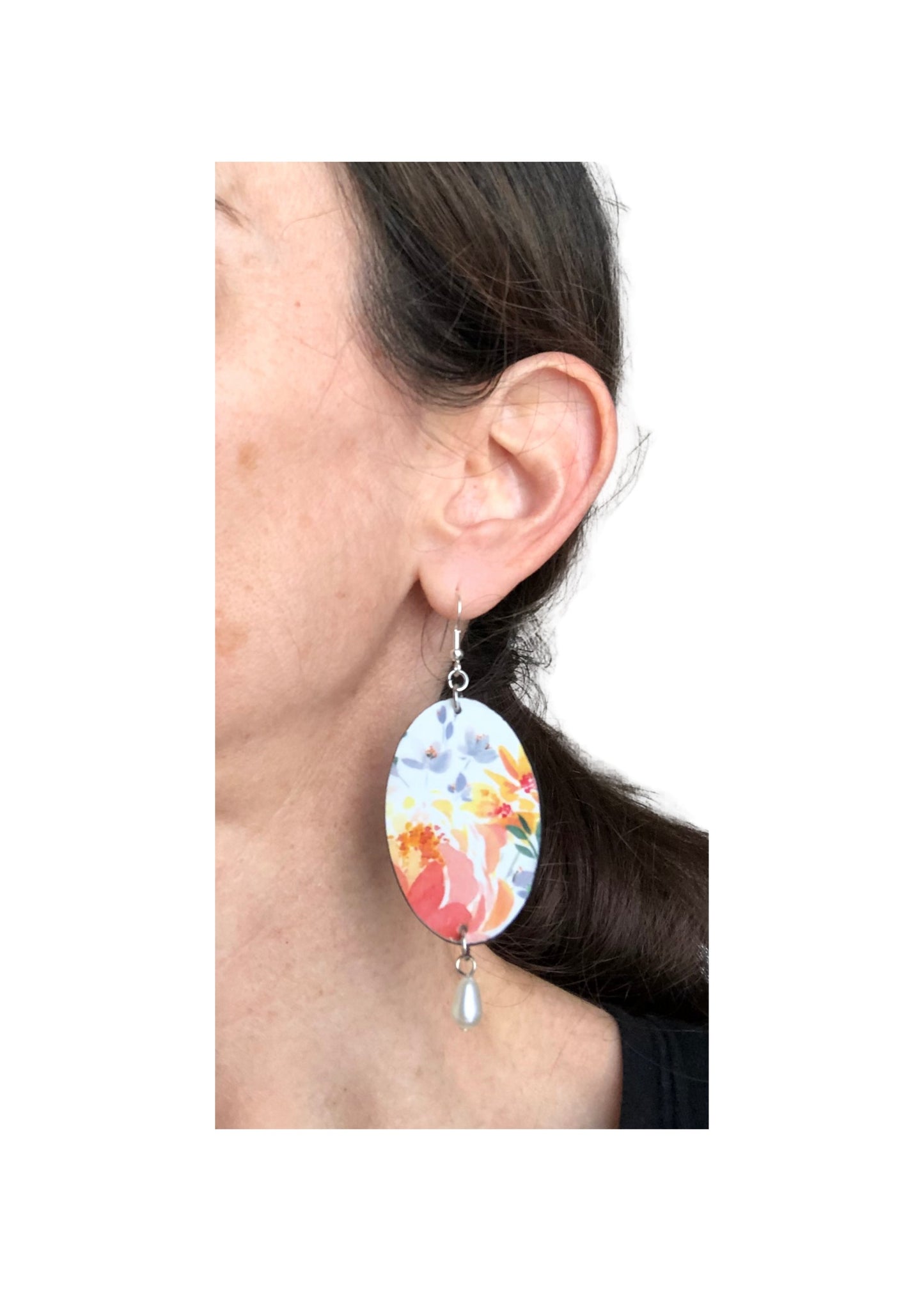 Earring with floral design worn by a person on a white background