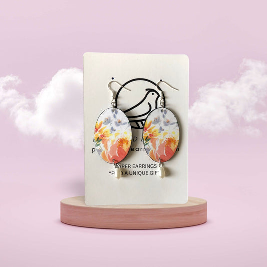 Floral earrings on a display card with a pink background
