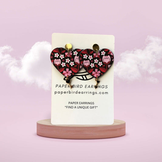 Heart-shaped earrings on a stand with a pink background