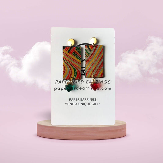 Colorful paper earrings on a white card with 'Papertbird Earrings' branding against a pink background.