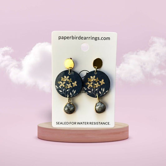 Pair of earrings on a branded card with a soft pink background