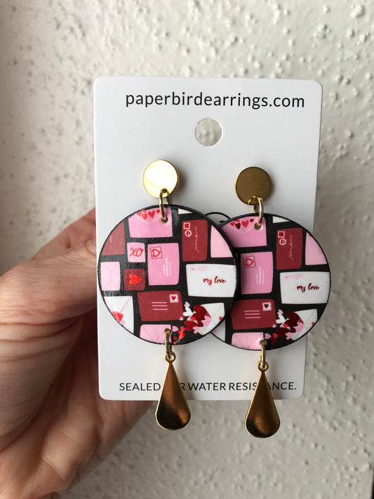 Pair of round paper earrings with a love letter patterned design 
