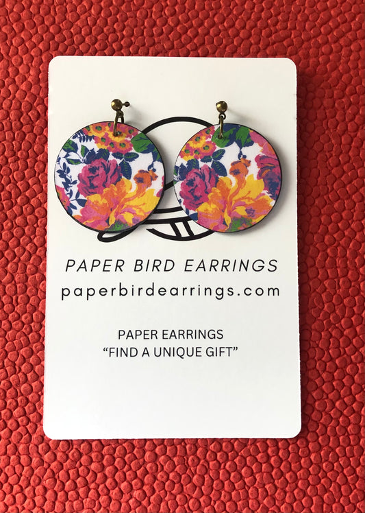 A pair of round floral patterned earrings on a white card with 'PAPER BIRD EARRINGS' written at the top.