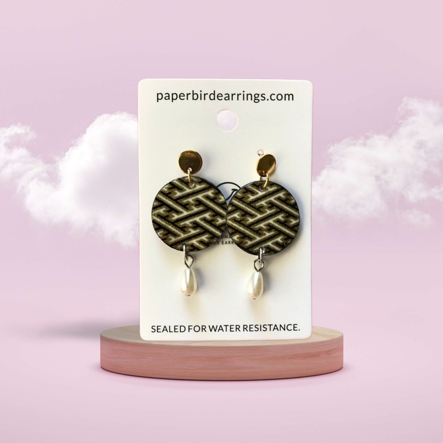 Earrings on a branded card with a pink background