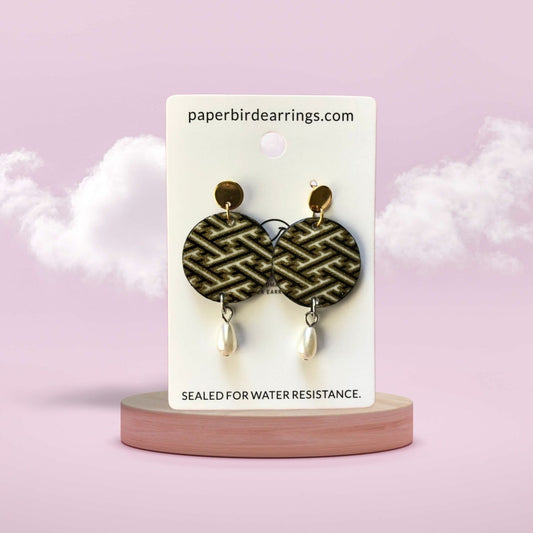 Earrings on a branded card with a pink background
