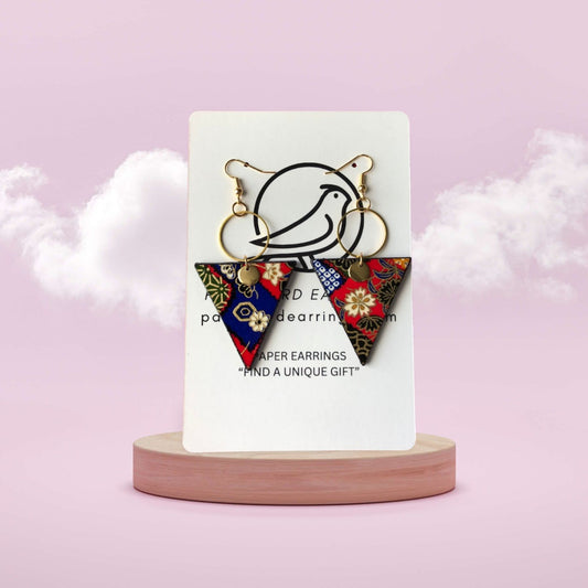 Colorful paper earrings on a white card with a pink background