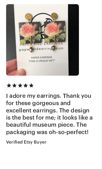 Handmade paper earrings with a floral design on a black background, displayed on a card.