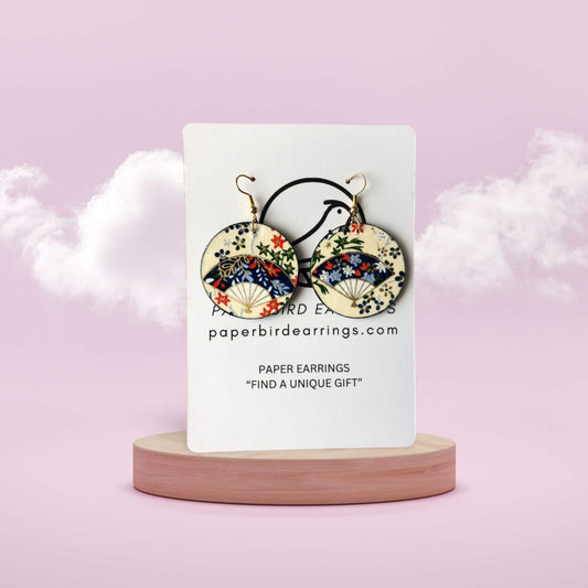 Paper earrings on a display card with a pink background