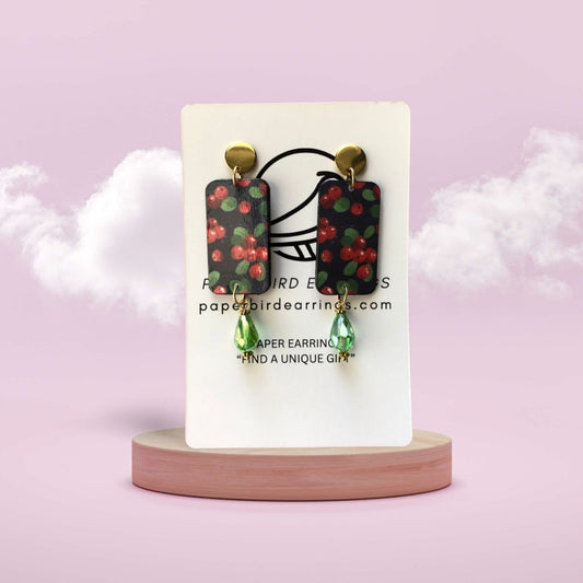 Earrings on a display card with a pink background