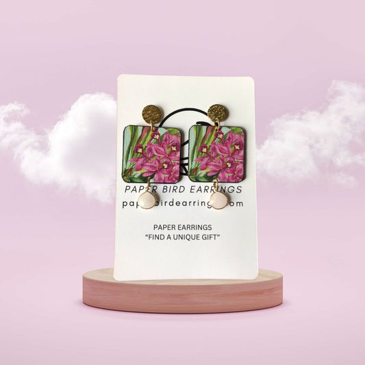 Paper bird earrings on a display card with a pink background