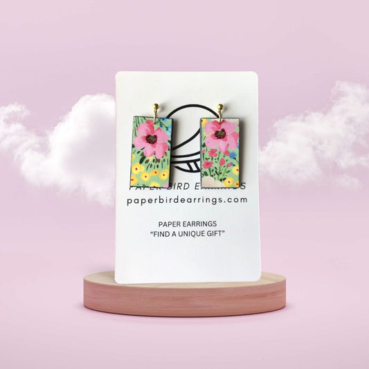 Floral paper earrings on a display card with a pink background