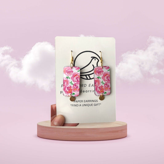 Floral earrings on a card with a pink background