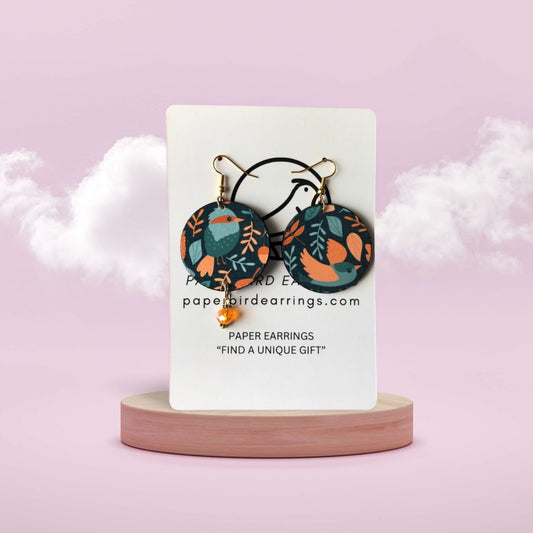 Pair of floral-patterned earrings on a white card with 'paperbirdearrings.com' text, against a light pink background.