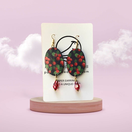 Earrings on a display card with a pink background