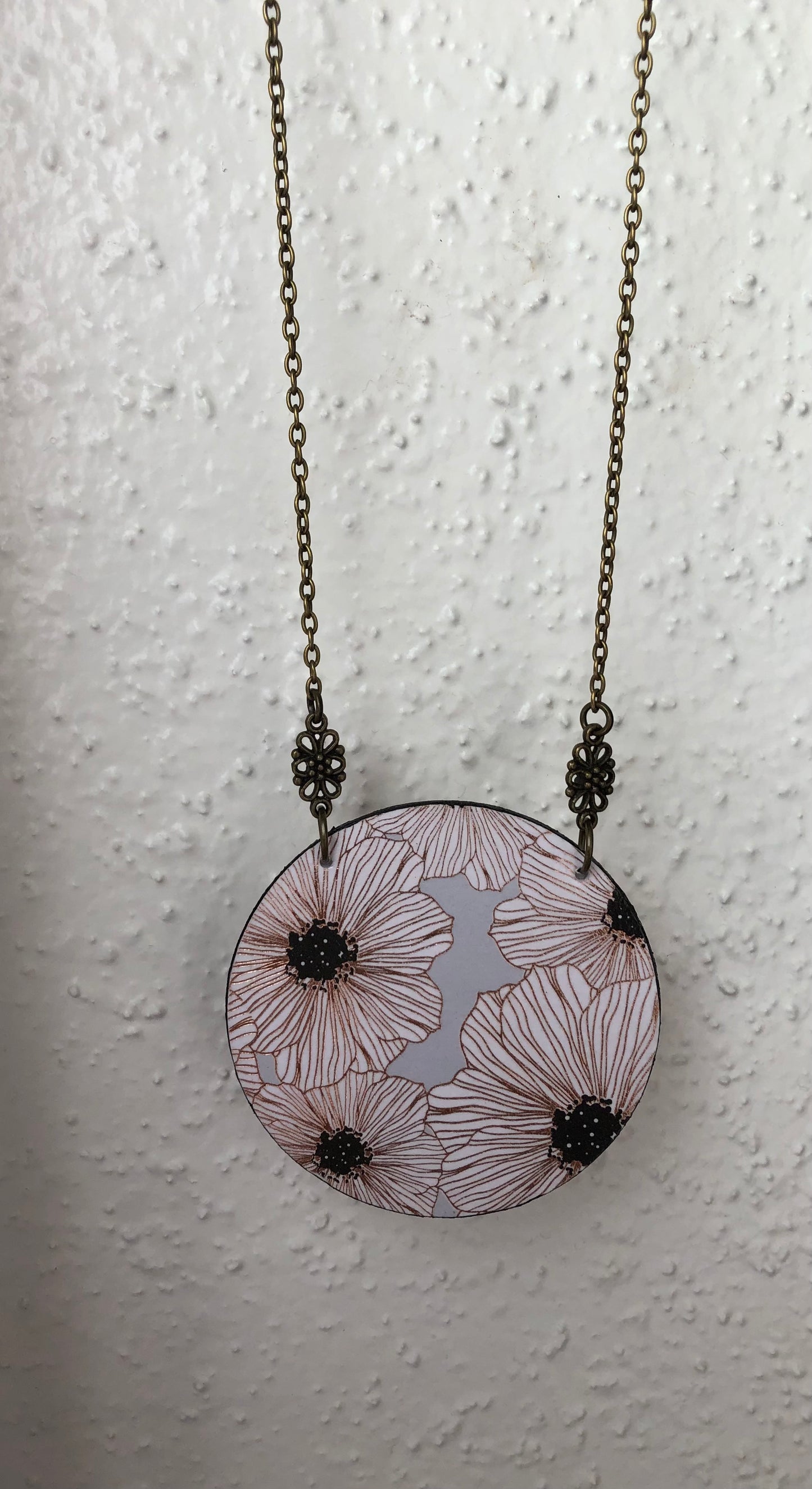 Necklace with a circular pendant featuring floral white and gray design