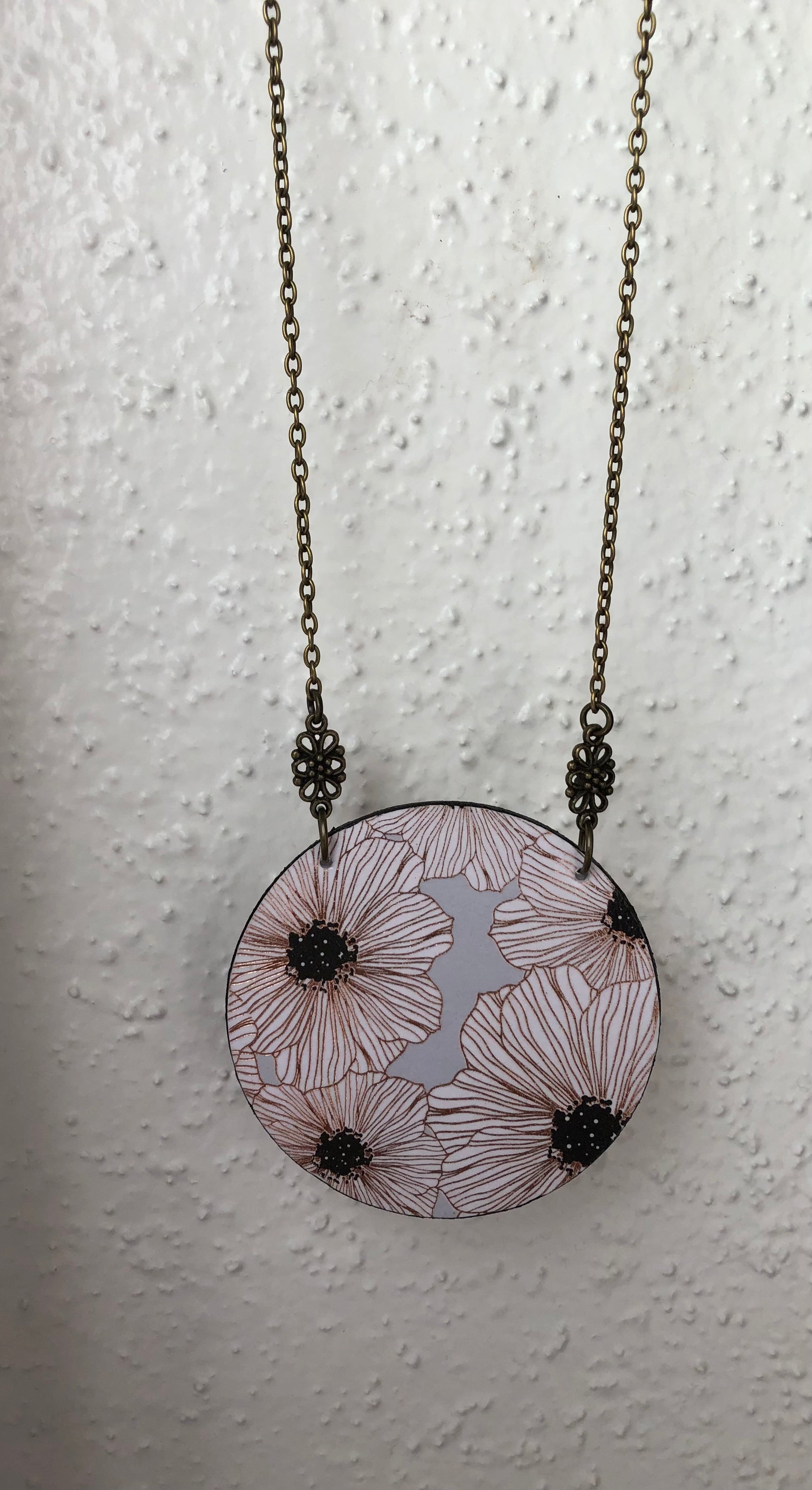 Necklace with a circular pendant featuring floral white and gray design