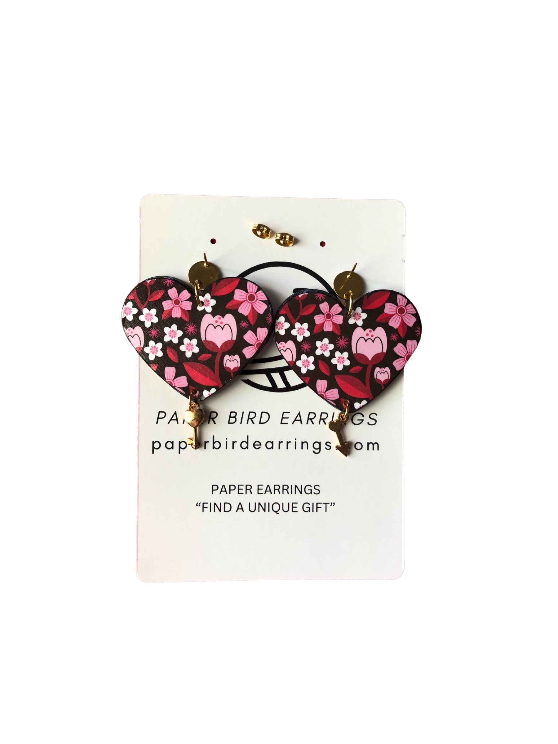Heart-shaped paper bird earrings on a display card with branding information.