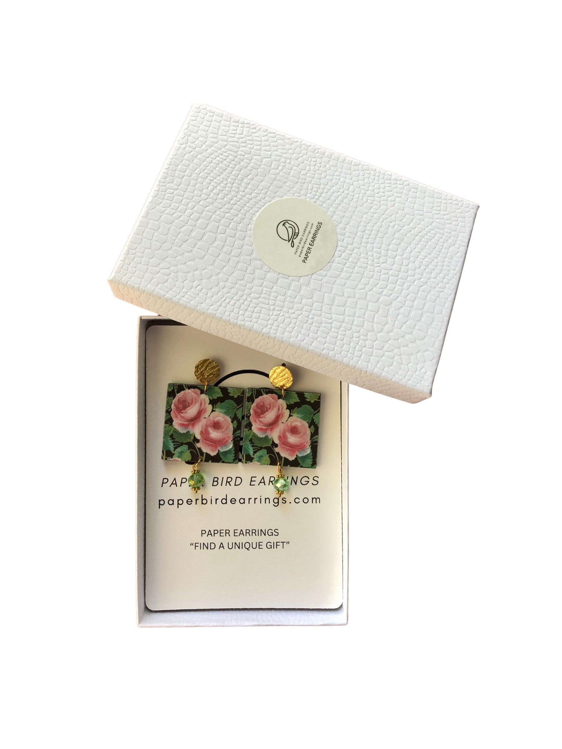 Box of paper bird earrings with a decorative label on a white background