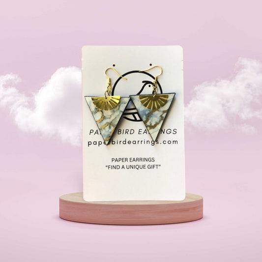 Triangular earrings on a display card with a pink background